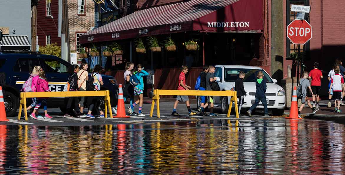Pedestrians cross a flooded street.