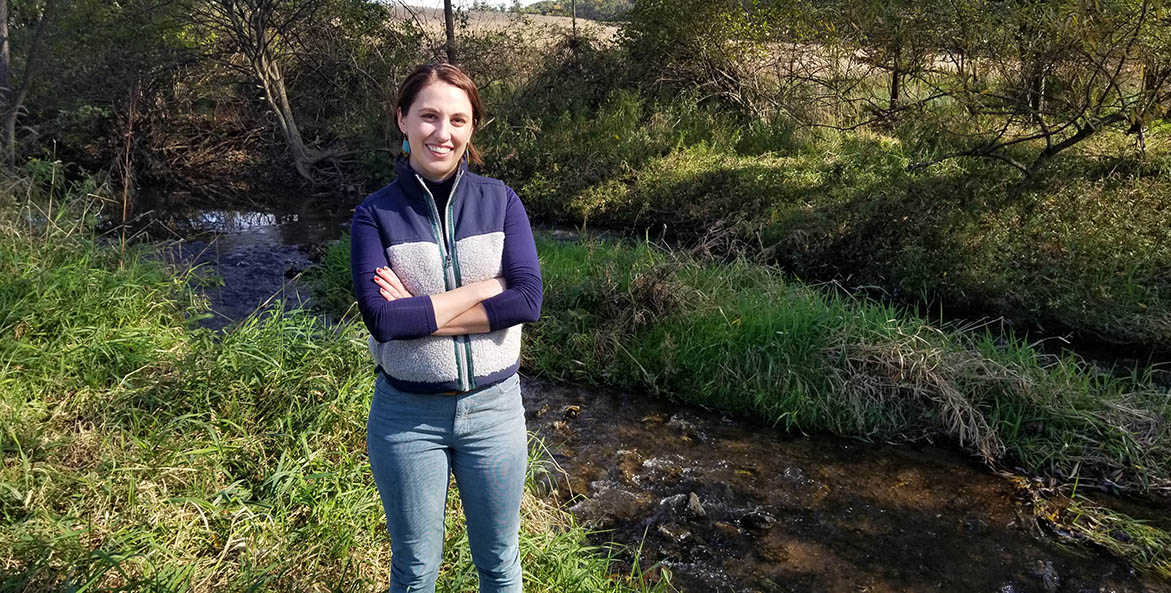 Woman standing next to a stream.