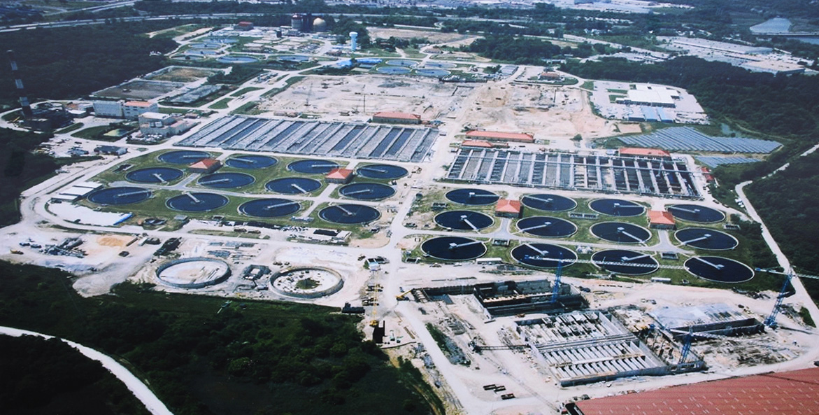 Round and rectangular treatment tanks spread across several acres surrounded by woods.