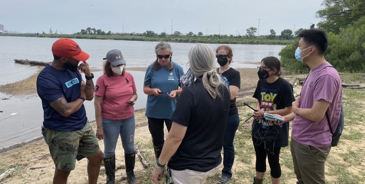 Group of teachers on a beach with water quality testing tools.