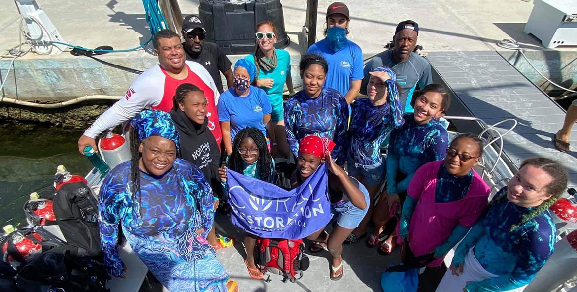 Group of students and adults in swim gear on a scuba diving boat.