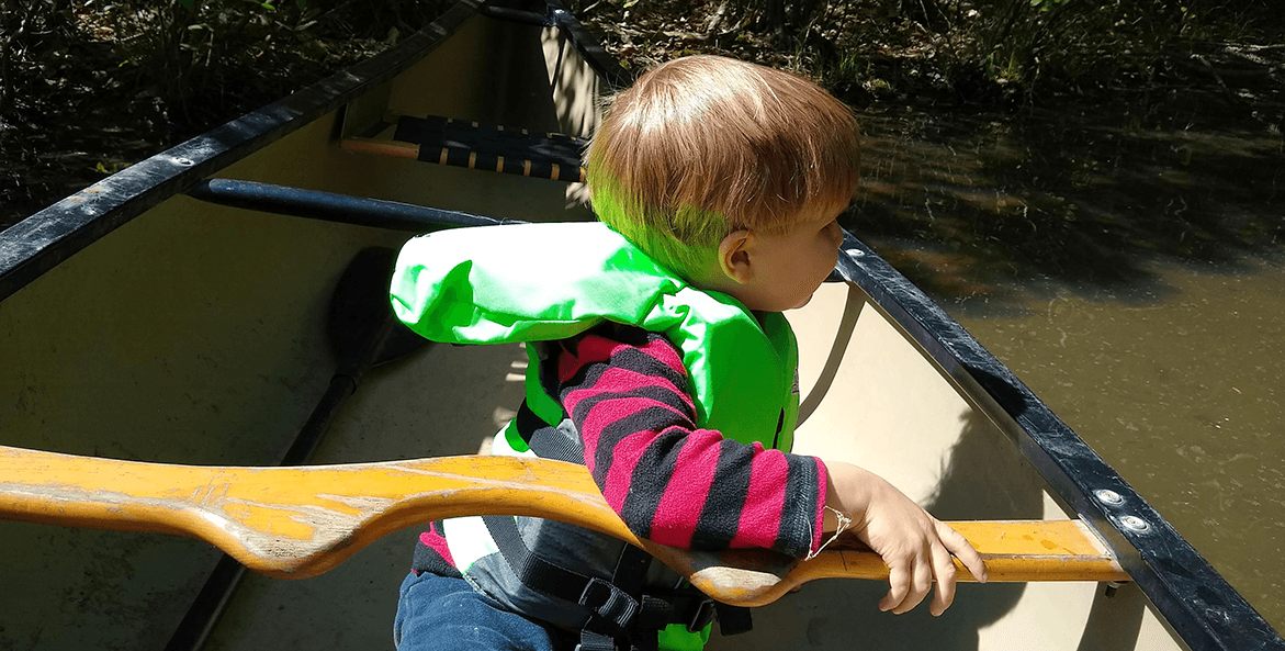 Child on a canoeing trip wearing a life jacket.