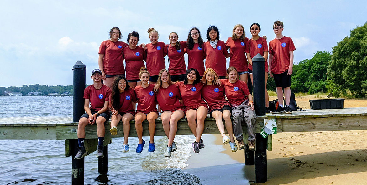 A group of students stand on a dock