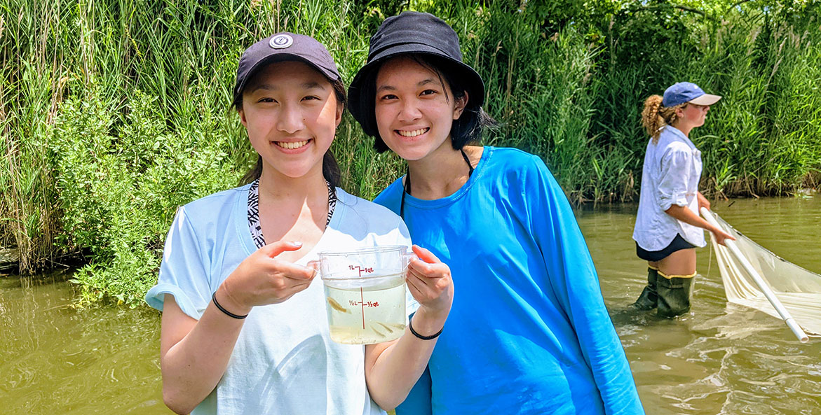 Two girls holding a bucket of water