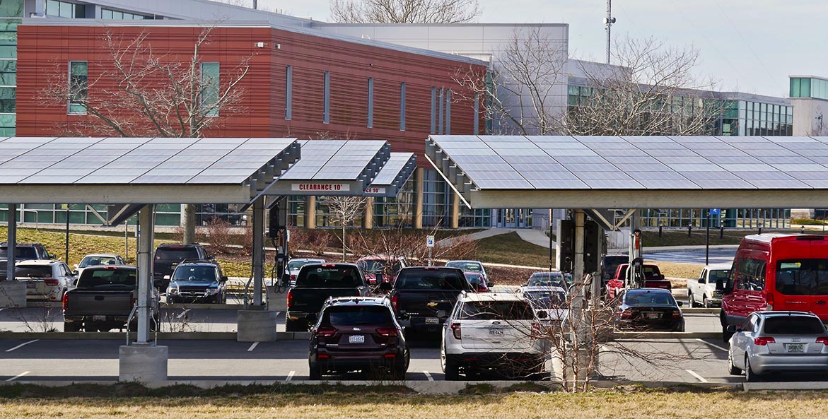 Cars are parked under solar arrays in a school parking lot.