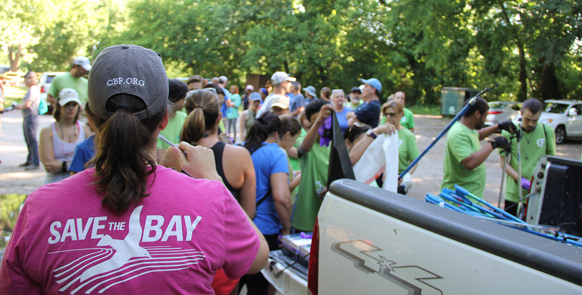 A group of people gathers for a cleanup, with CBF gear in the foreground