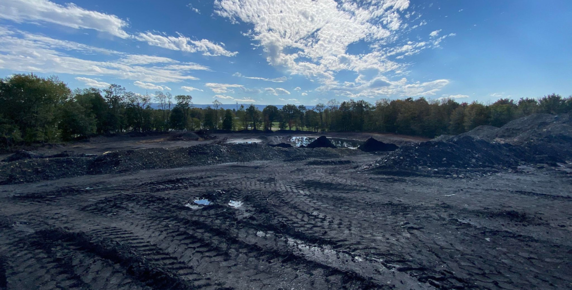 An abandoned silt basin on Luzerne County, Pennsylvania stretches out underneath a blue sky, speckled with white wispy clouds.