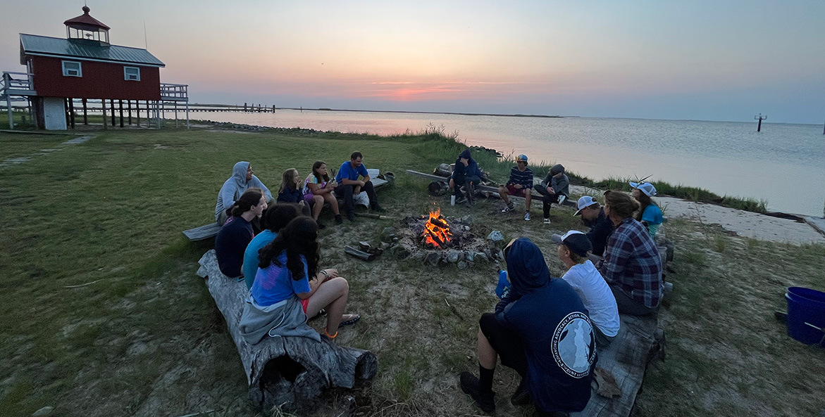 Students enjoy a relaxing bonfire at sunset.
