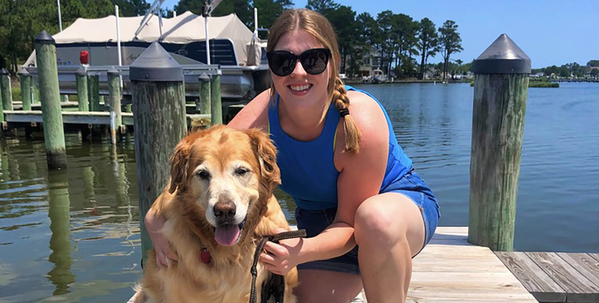 A woman with her dog on a dock.