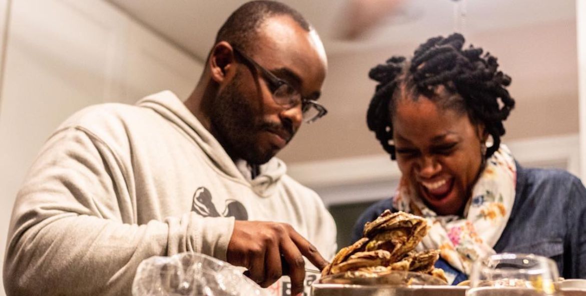 Two people shuck oysters together.