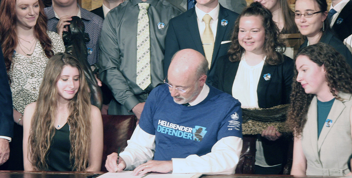 Pennsylvania Governor Tom Wolf signs a bill, surrounded by smiling students