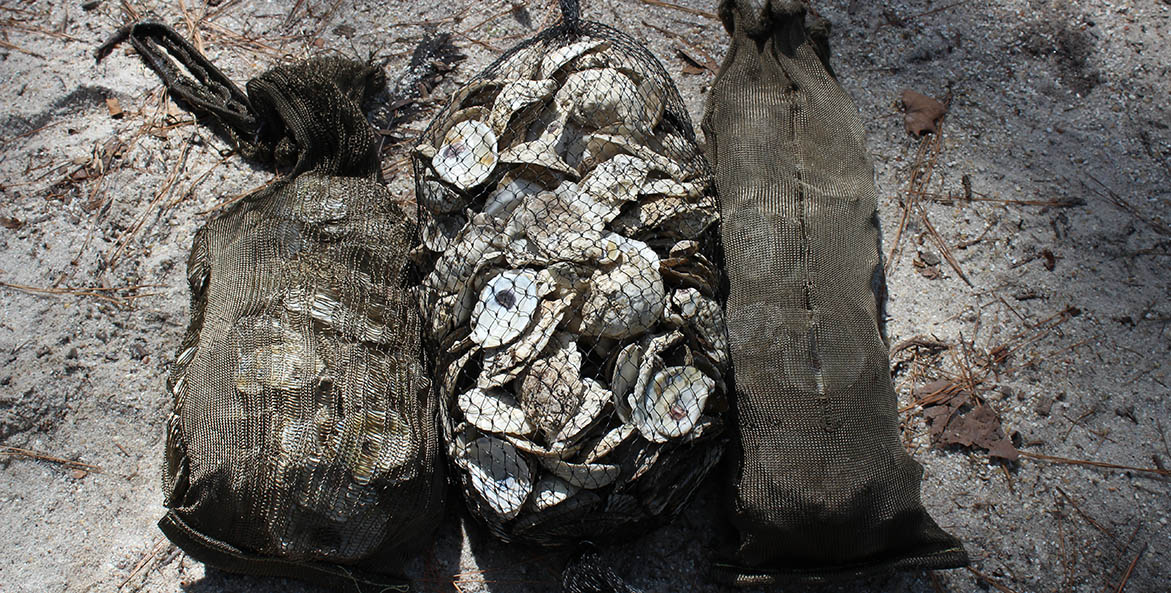 Two basalt fiber oyster shell bags on either side of a traditional mesh oyster shell bag.
