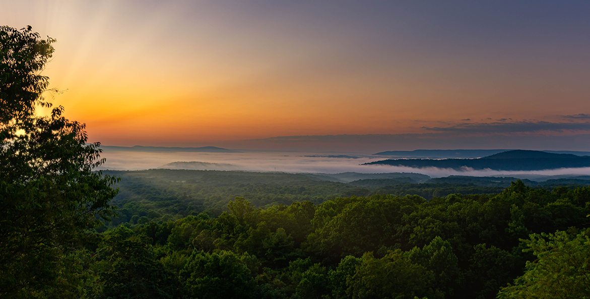 The sun sets over rolling hills of Maryland forests.
