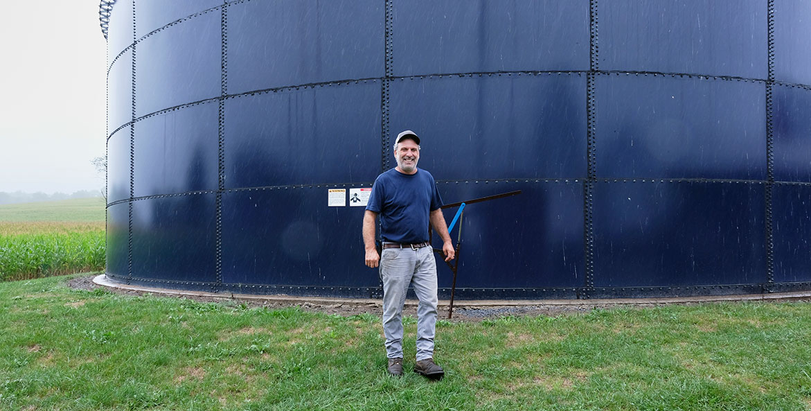 Man walking past silo on a farm