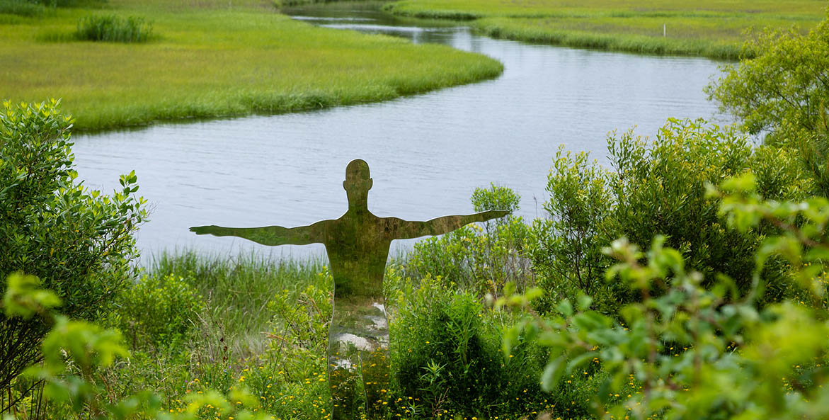 Part of a sculpture showing a human figure overlooks peaceful Paradise Creek.