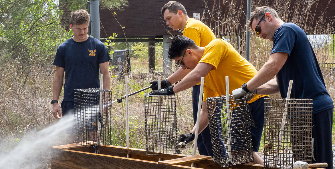 Four sailors spray cages with water