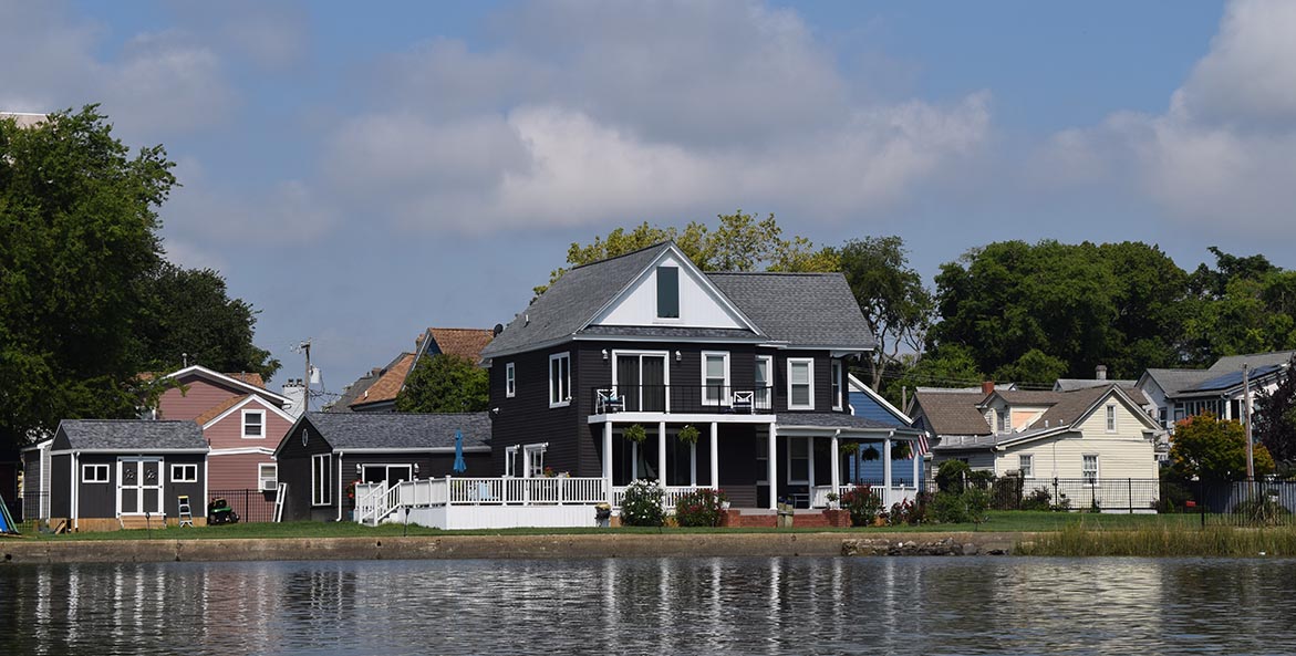 Dark grey and white house, viewed from a river.