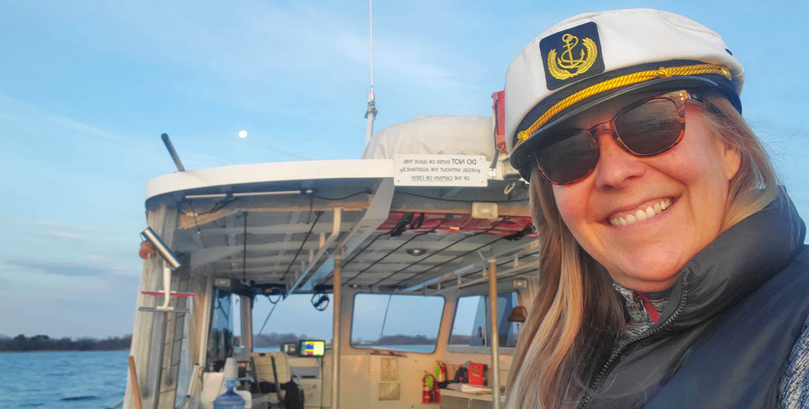 Woman wearing a captain's hat on a boat.