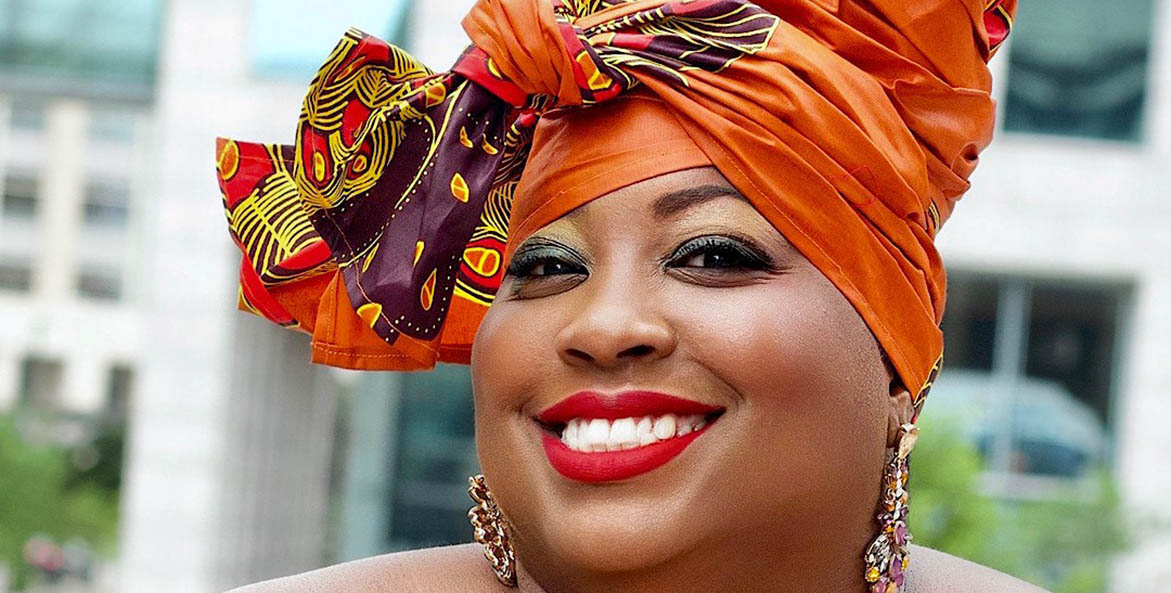 Close up of a smiling woman with an orange head scarf. 