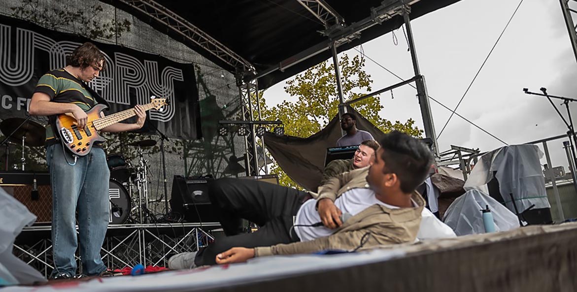 A young man plays guitar on a stage.