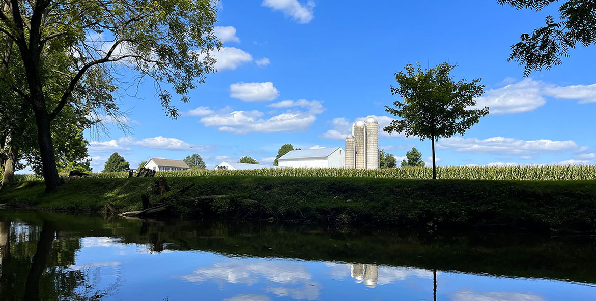 The Upper Conestoga River with clouds reflected and a farm in the background