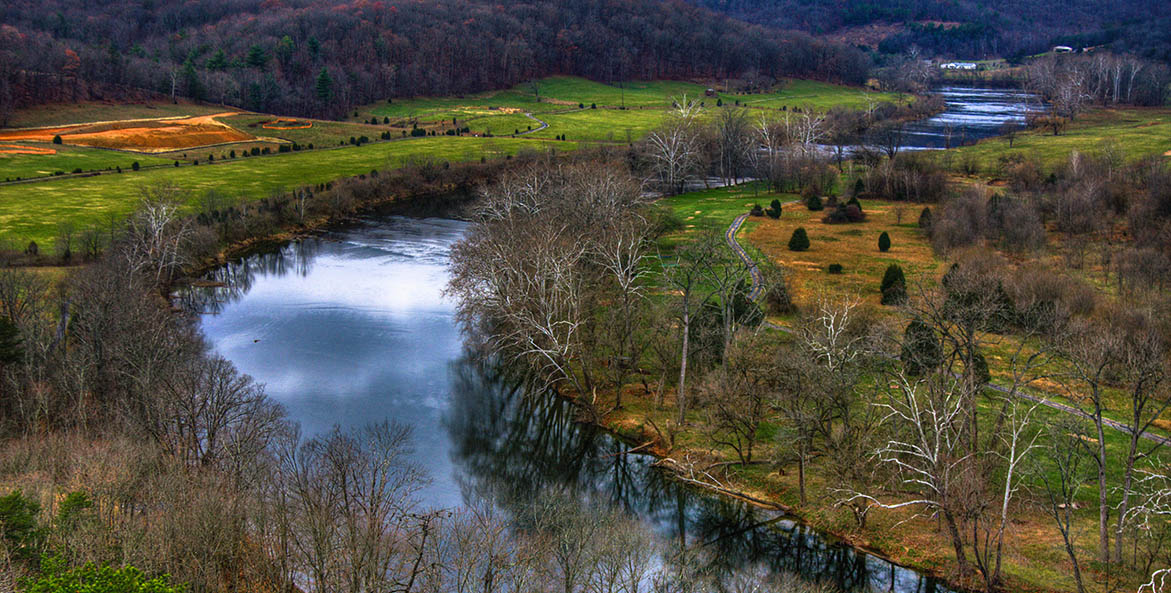 The South Fork of the Shenandoah River, flanked by trees, meanders through fields.