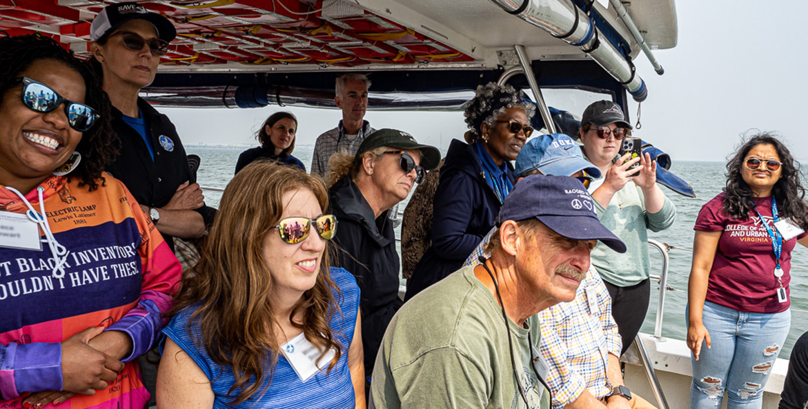 A group of people sit and stand in the stern of a CBF education vessel.