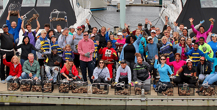 Dozens of residents wave and display their oyster gardening cages on a pier in Baltimore.