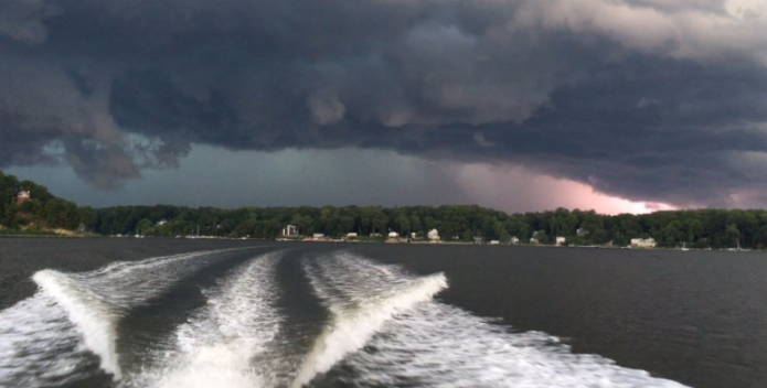 Image of a boat outrunning an approaching storm.
