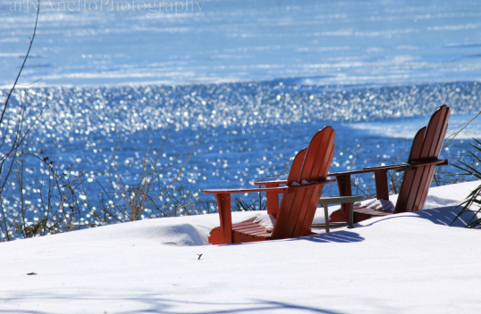 Image of two adirondack chairs covered in a blanket of snow.