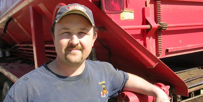 Close-up of man standing in front of farm equipment.