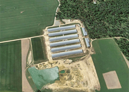 Aerial photo of farmland with six long, narrow buildings.