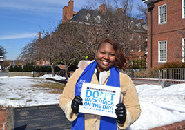 Devan Ogburn holding a sign saying: Don't Backtrack on the Bay.