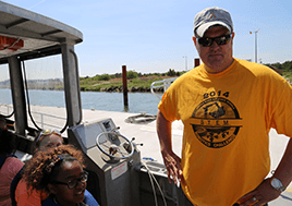 Dr. Aaron Spence stands in a boat surrounded by students.