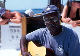 Earl White plays guitar on a pier. 