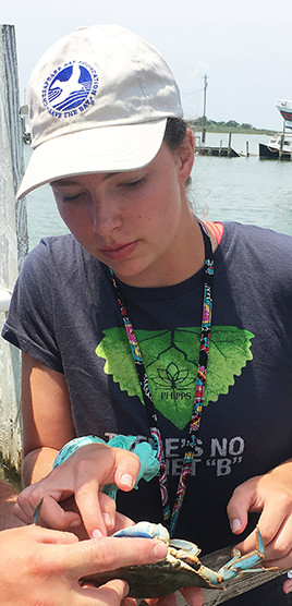 Student leader Emma Stone examines a blue crab.
