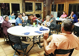 Men and women sit around tables talking inside of the Port Isobel Education Center.