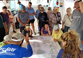 Men and women stand around a table looking at a map of the Chesapeake Bay.