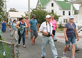 Men and women walk down a road lined with homes.