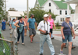 Men and women walk down a road lined with homes. 