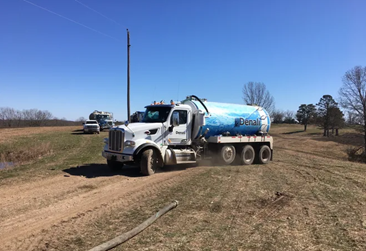 Truck with a blue tank on a dirt road.