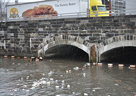 Trash in the water beneath a bridge is a very visible sign of polluted runoff.