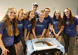 Student Leadership Coucil members stand around a tank holding Heather.