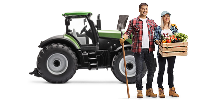 Man and woman farmers standing in front of a tractor.