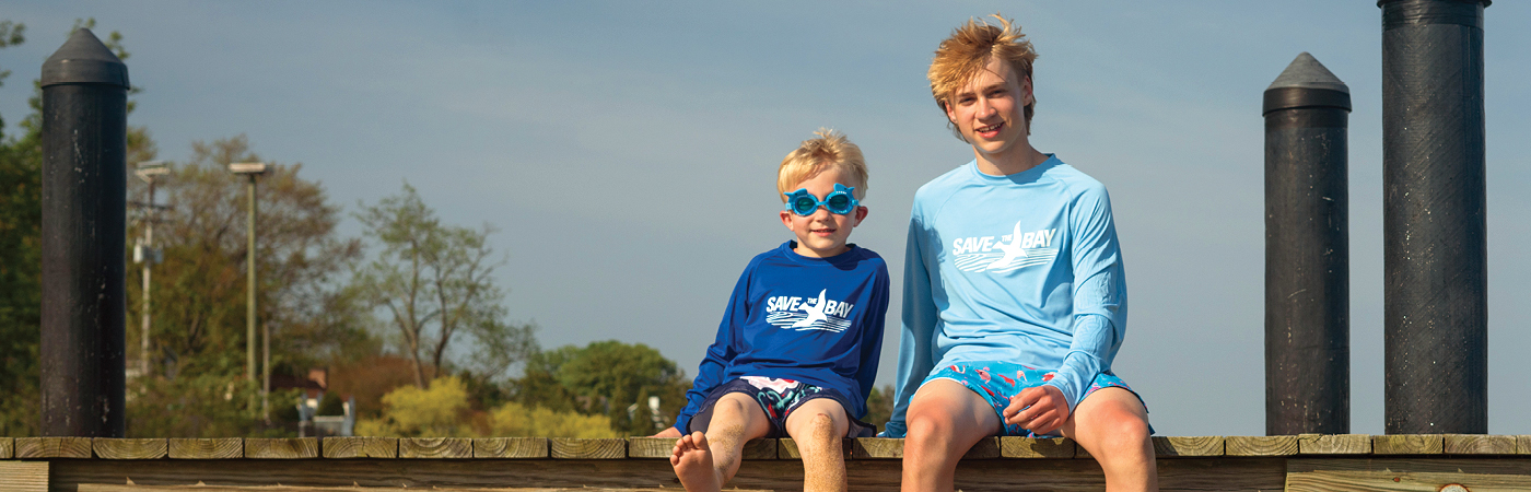 Two young boys sit on a pier, wearing CBF t-shirts.