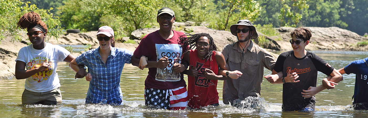 Students linking arms wading in the Susquehanna River.
