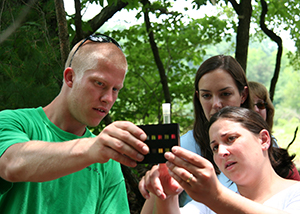 Photo of three people examining a pH test of a water sample.