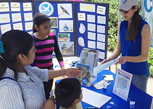 Photo of a CBF volunteer speaking with a woman and her children at CBF's festival booth.