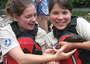 Photo of two female students holding a hellbender salamander