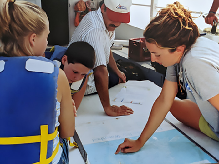 A teacher points out a location on a map of the Bay to students aboard a CBF education vessel.
